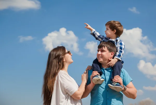 Familia de tres personas, padres jóvenes y un hijo pequeño en un fondo del cielo — Foto de Stock