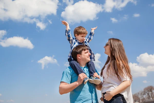 Familia de tres personas, padres jóvenes y un hijo pequeño en un fondo del cielo — Foto de Stock