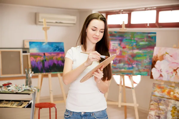 Female Artist Working On Painting In Studio