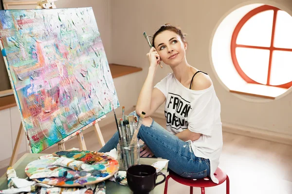 Young female artist working on painting in studio. — Stock Photo, Image