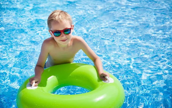 Malý chlapec plavání v bazénu s velkými světle zelené gumovým kroužkem, Bavíte se v aquaparku. — Stock fotografie