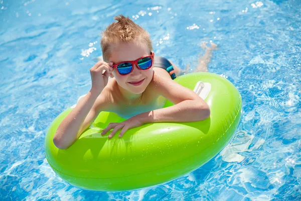 Malý chlapec plavání v bazénu s velkými světle zelené gumovým kroužkem, Bavíte se v aquaparku. — Stock fotografie