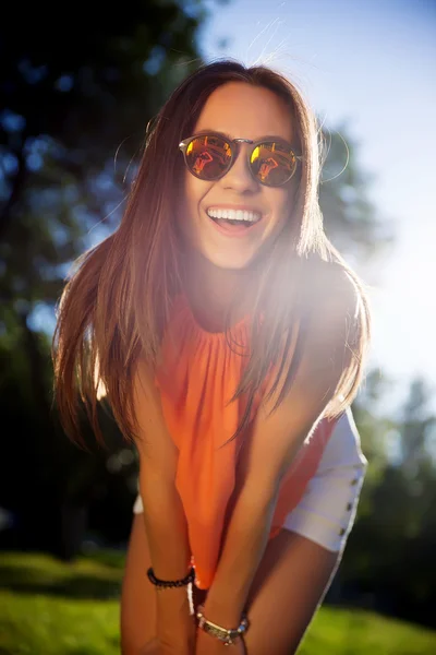 Linda garota hipster em óculos de sol sorrindo e olhando para a câmera — Fotografia de Stock