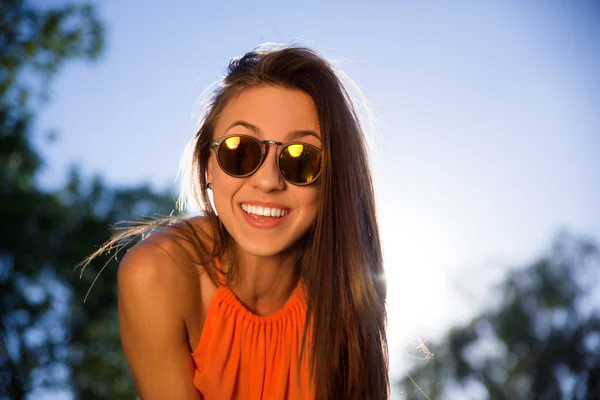 Szép csípő lány napszemüveg és mosolyogva néz a kamerába — Stock Fotó