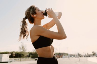 Atletik kadın mola verip su içiyor..