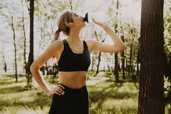 Woman Runner Using Earphones Takes Break Drinking Water Royalty Free Stock Photos