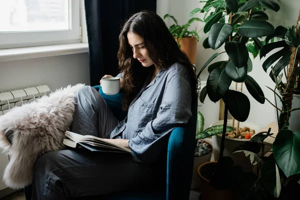 Kadın Evde Rahat Bir Sandalyede Otururken Kitap Okuyor — Stok fotoğraf