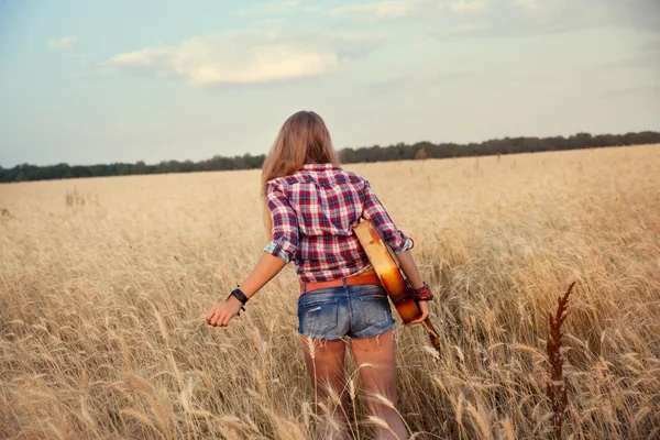 Стройная девушка с гитарой, бегущей по пшеничному полю — стоковое фото