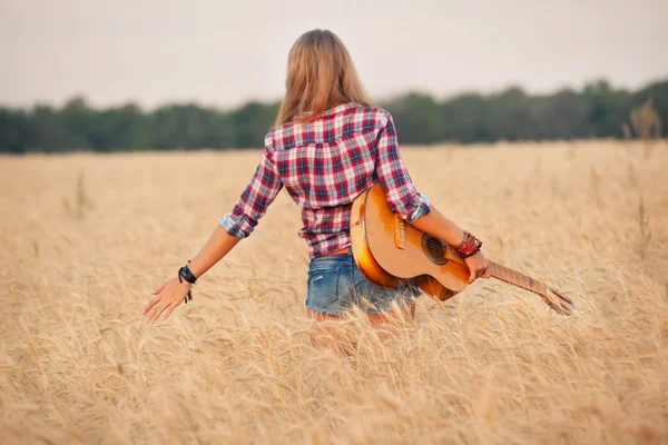 Szczupła dziewczyna z gitarą w polu pszenicy. — Zdjęcie stockowe