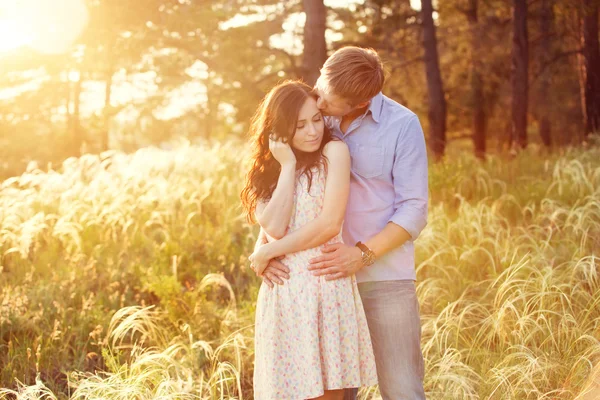 Young couple in love at sunset in the field — Stock Photo, Image