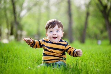 küçük çocuk bir yeşil çimenlerin üzerinde oturur