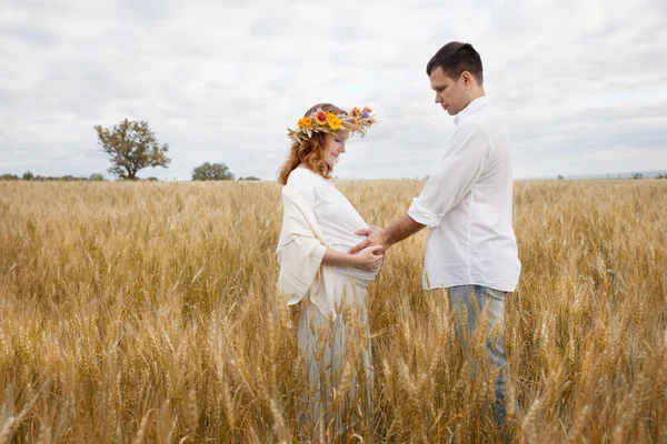 Outdoor portrait of young pregnant couple in field — Stock Photo, Image