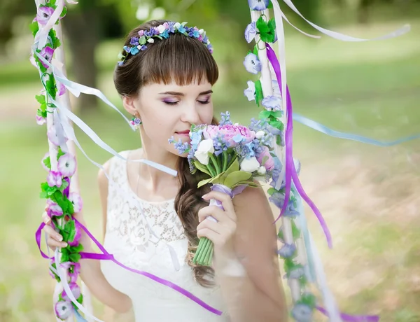 The beautiful bride on a swing under a tree — Stock Photo, Image