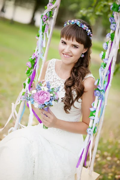 Krásná nevěsta na houpačce pod stromem — Stock fotografie