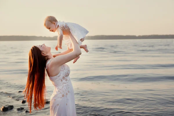 Mãe feliz e filha se divertindo na praia do pôr do sol — Fotografia de Stock