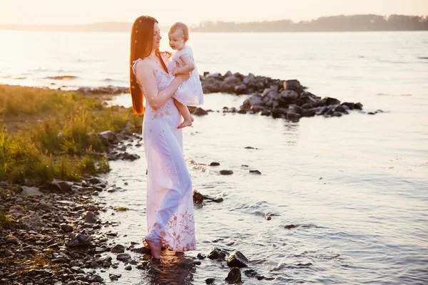 Šťastná matka a dcera, zábava na pláži při západu slunce — Stock fotografie