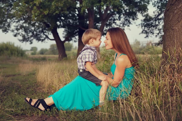 Mãe e filho sentados face a face no campo — Fotografia de Stock