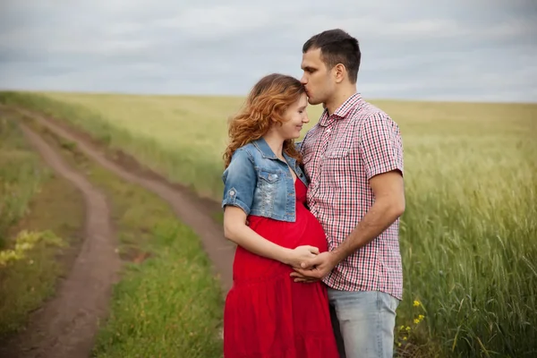Zwangere vrouw en haar echtgenoot wandelen in het platteland — Stockfoto