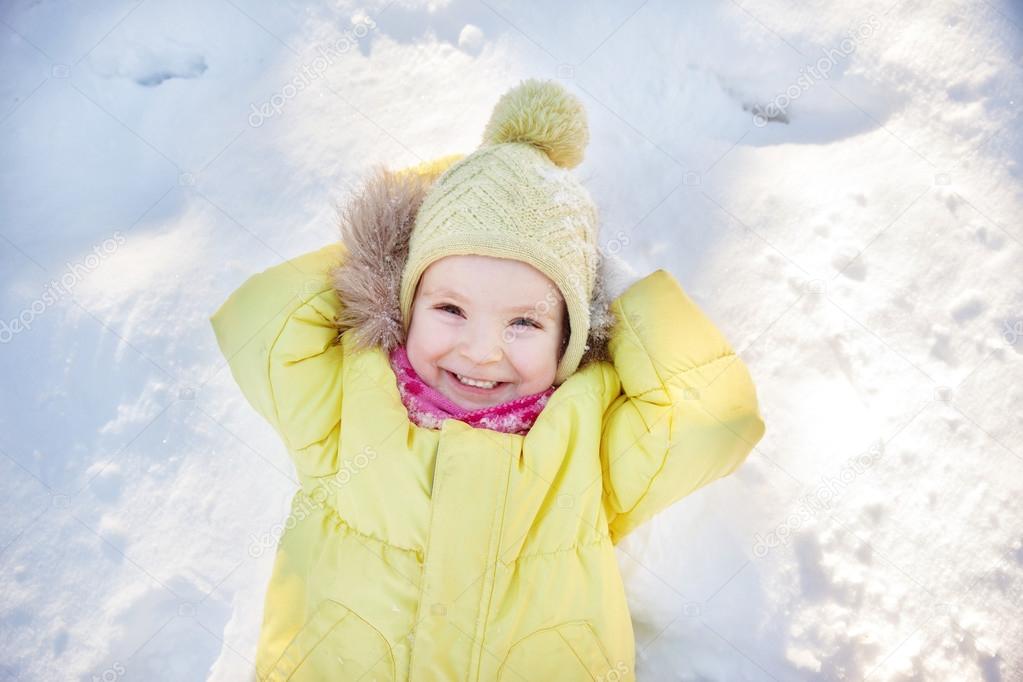 Little girl lying on snow