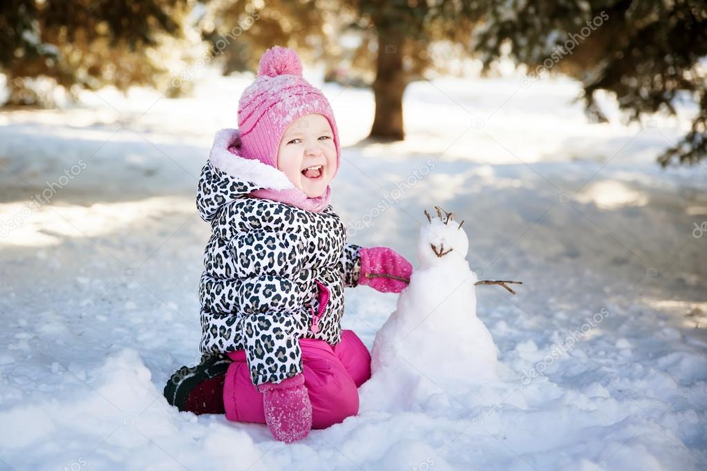 little girl playing with a snowman