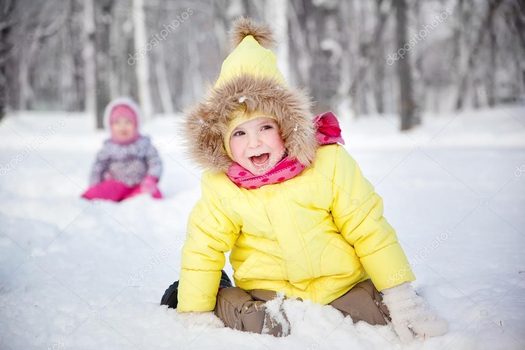 funny little girl in winter clothes in a snowy forest