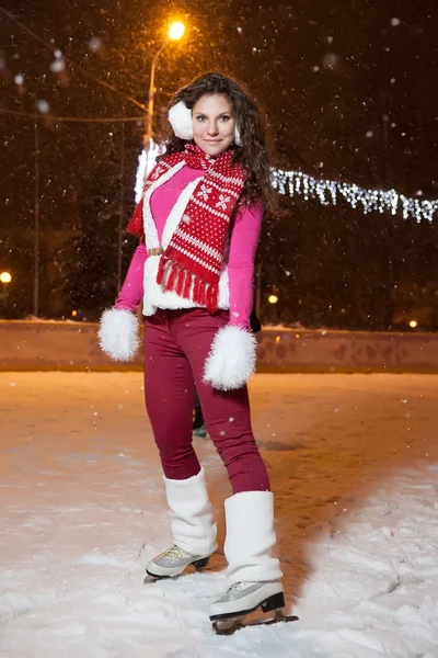 Mooi meisje op een ijsbaan in de winteravond — Stockfoto