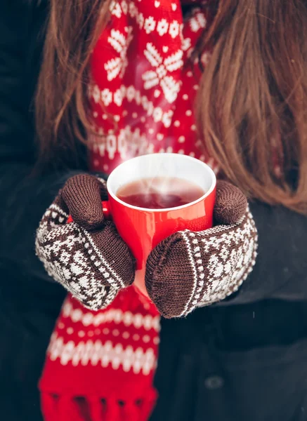 Frauenhände in Fäustlingen mit einer Tasse Tee — Stockfoto