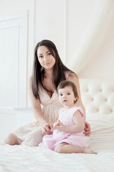 Joven madre con hija pequeña en el dormitorio — Foto de Stock