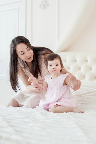 Молодая мать с маленькой дочерью в спальне — стоковое фото