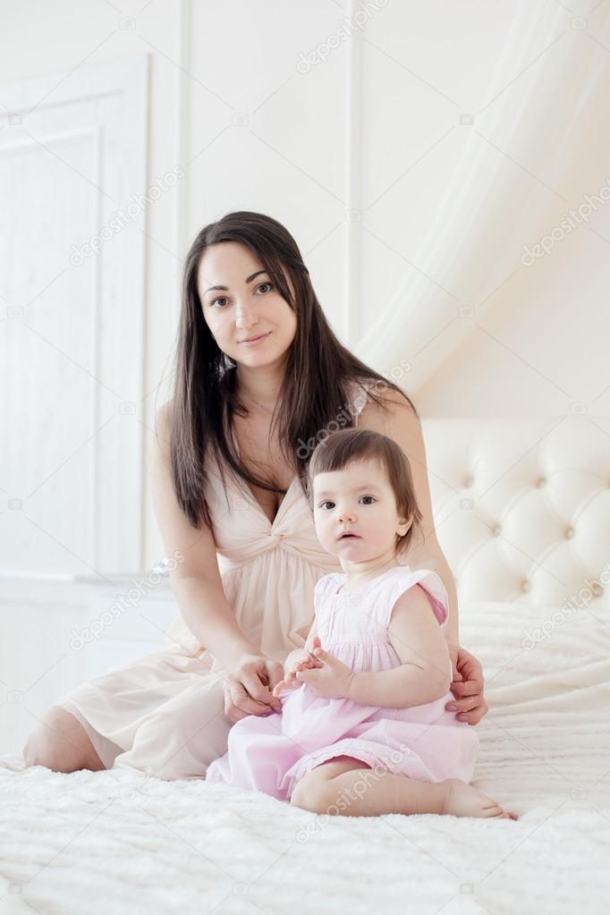 Young mother with little daughter in the bedroom