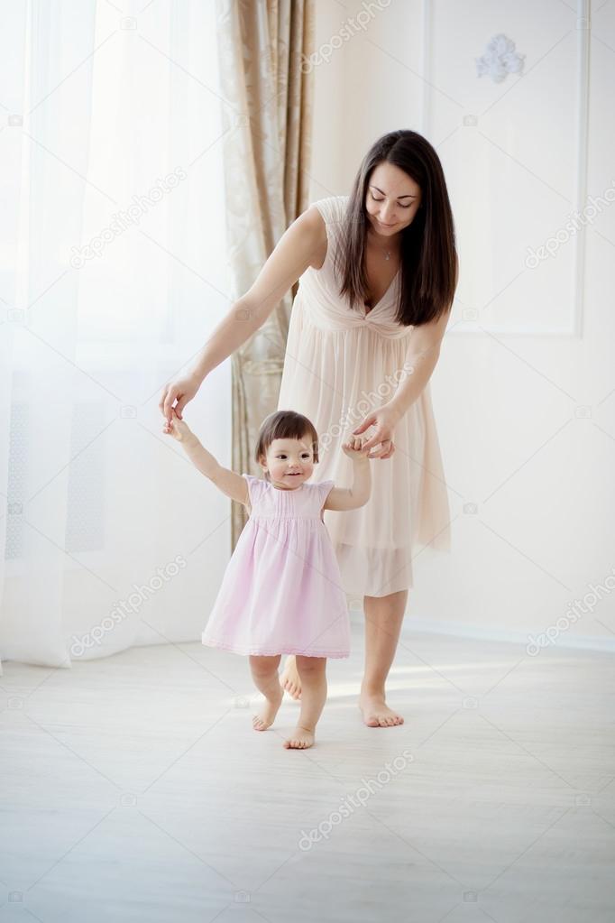 little girl first steps with the help of mom