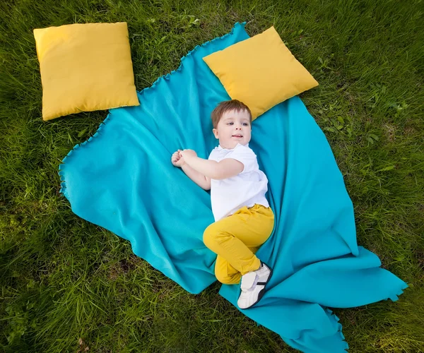 Petit garçon reposant sur la couverture dans le jardin d'été — Photo