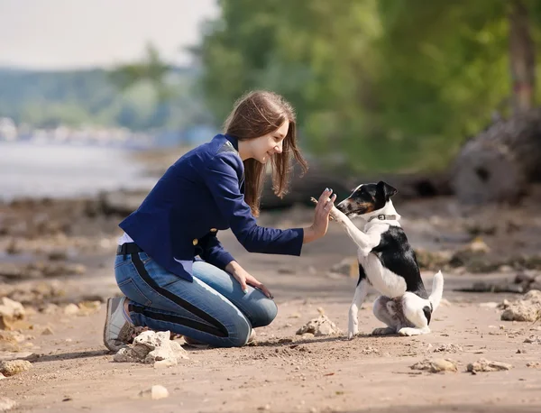 Jovem mulher com seu cão na praia — Fotografia de Stock