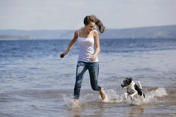 Meisje en de hond wordt uitgevoerd op een strand — Stockfoto