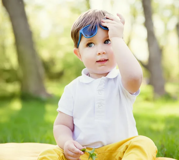 Маленький мальчик в очках на лужайке — стоковое фото