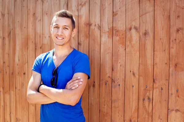 Handsome young man at the wooden wall — Stock Photo, Image