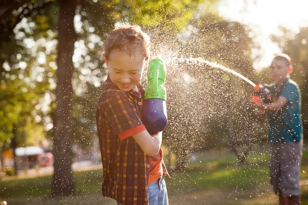 Niños pequeños felices jugando con pistolas de agua —  Fotos de Stock