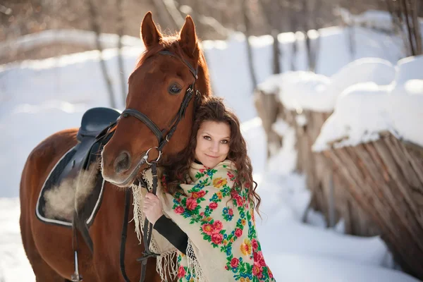 Beautiful young woman in Russian national scarf with a horse in the countryside in winter — Stock Photo, Image