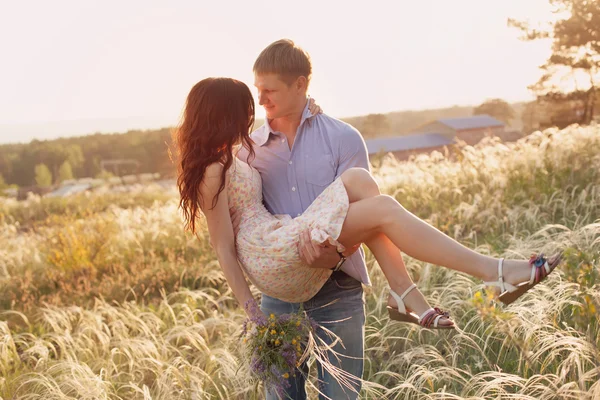 Lovers walking in a field at sunset — Stock Photo, Image