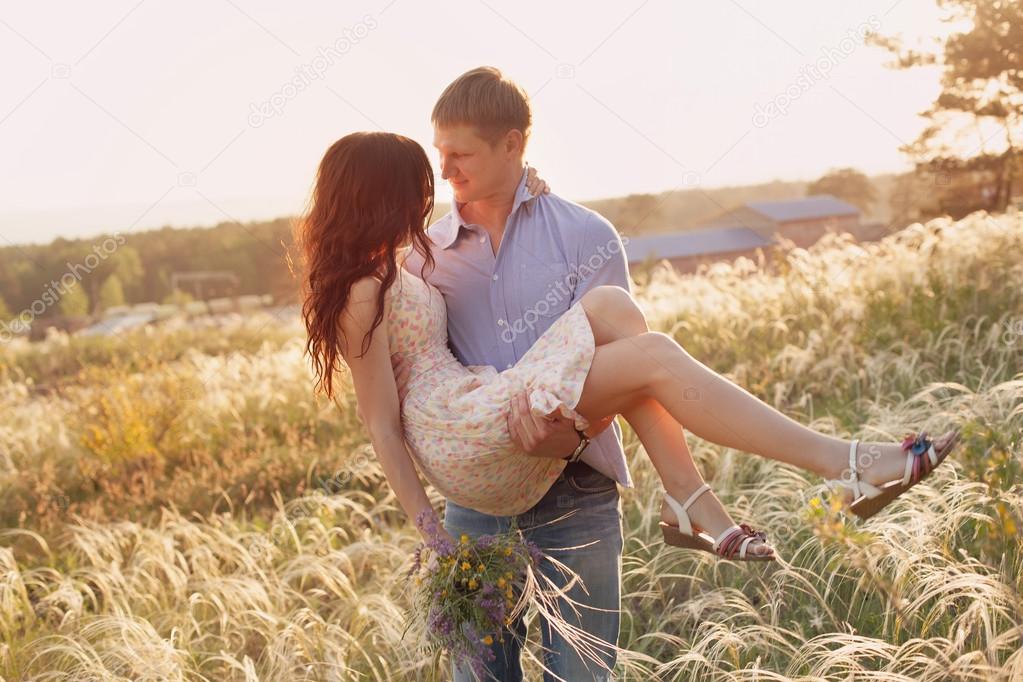 lovers walking in a field at sunset