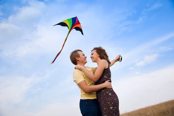 Feliz jovem casal apaixonado por voar um papagaio no campo — Fotografia de Stock