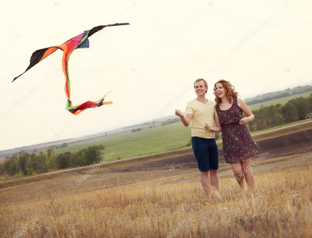 Happy young couple in love with flying a kite at countryside