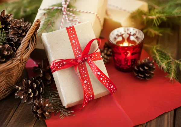 Christmas presents basket with pine cones and a candle on a wooden table — Stock Photo, Image