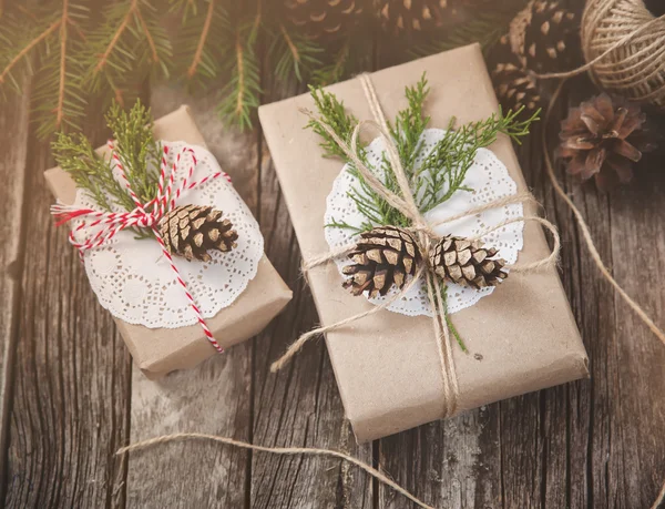 Hand crafted gift on rustic wooden background with cones, toned image — Stock Photo, Image