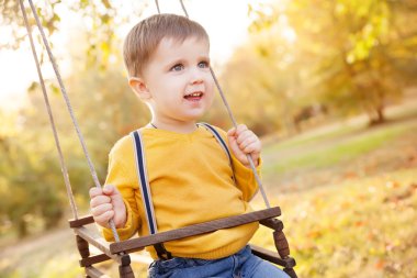 Mutlu bebek çocuk eğleniyor bir salıncak binmek bir sonbahar gün Bahçesi