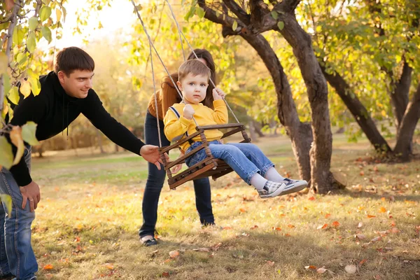 Familia feliz divirtiéndose en un paseo en un jardín un día de otoño — Foto de Stock