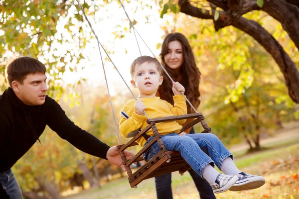 Happy family having fun on a swing ride at a garden a autumn day — Stock Photo, Image