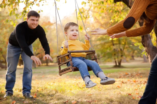 Famiglia felice divertirsi su un giro swing in un giardino una giornata d'autunno — Foto Stock