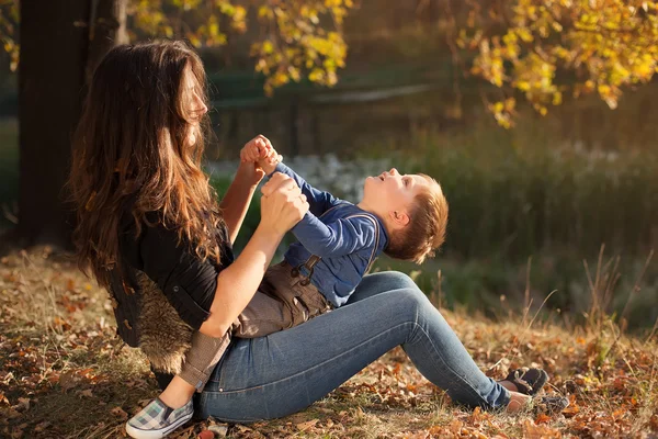 Felice madre che gioca con suo figlio all'aperto in autunno — Foto Stock