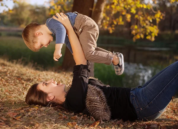 Glad mamma leker med hennes son utomhus på hösten — Stockfoto